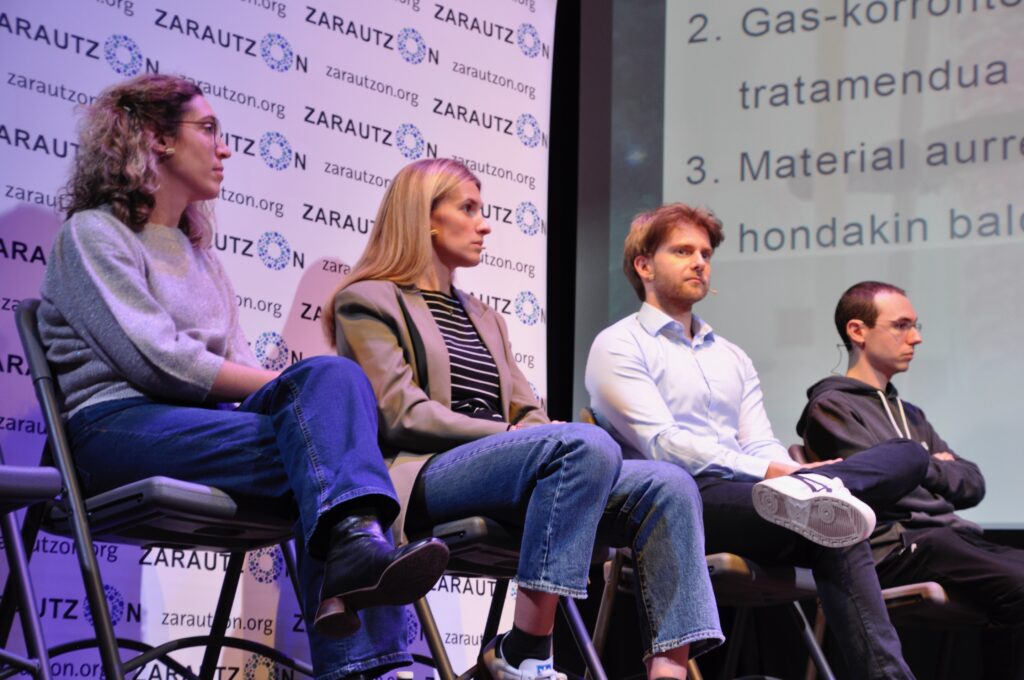 Cuatro ponentes sentados en el escenario ante el panel de ZarautzOn