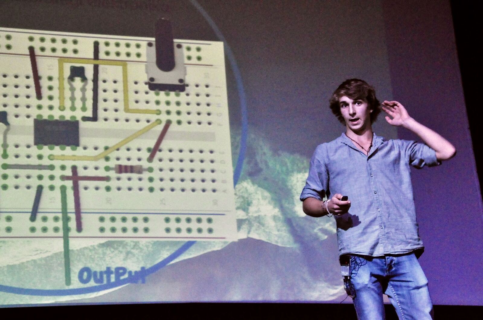 Un joven ponente ante una diapositiva sobre electrónica